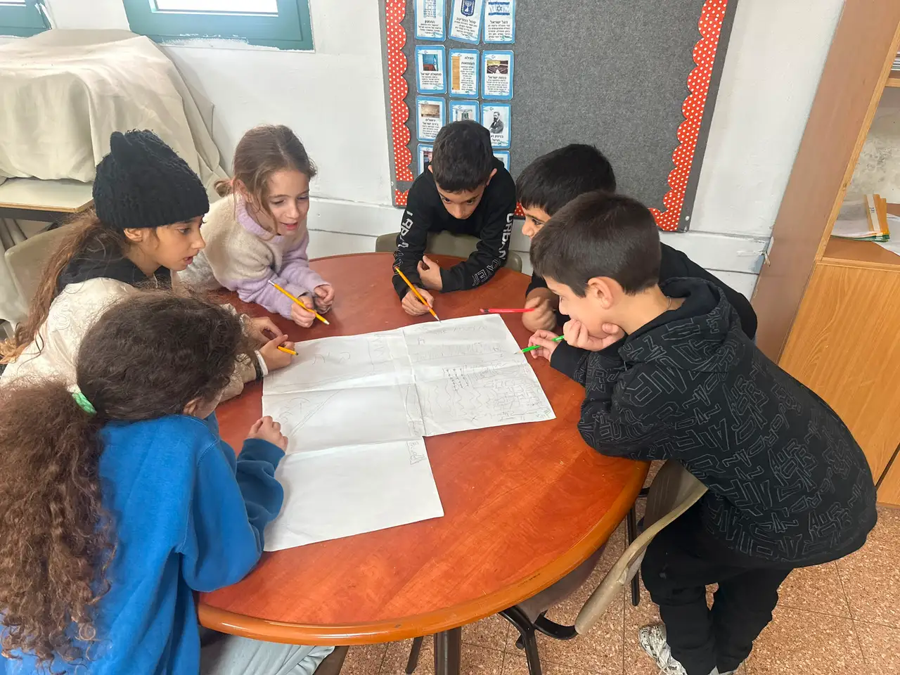 Students gathered around a table sketching a plan together before building it in Minecraft